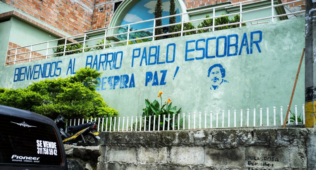 Mural bertuliskan Bienvenidos al Barrio Pablo Escobar dengan gambar wajah Escobar di sebuah permukiman di Medellín