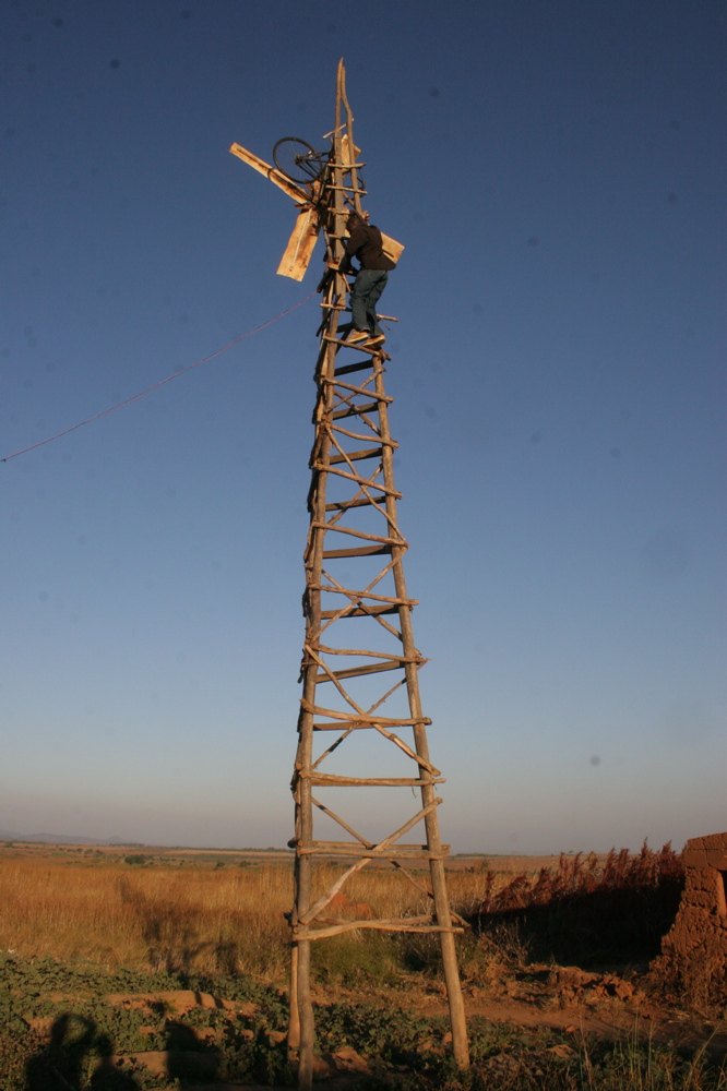 Menara kayu kincir angin buatan William Kamkwamba di Malawi dengan seseorang memanjat ke puncaknya