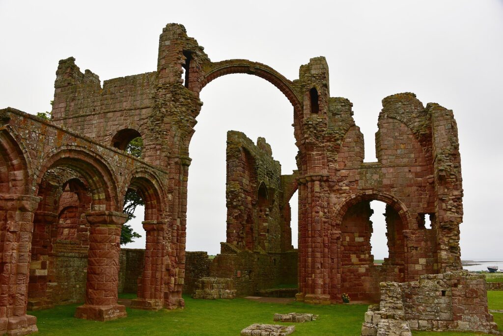 Reruntuhan lengkung batu merah Lindisfarne Priory di Pulau Lindisfarne, Northumbria, Inggris